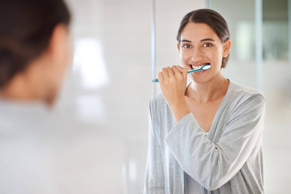 Woman using xylitol gum and toothpaste for oral health in Bondi Beach